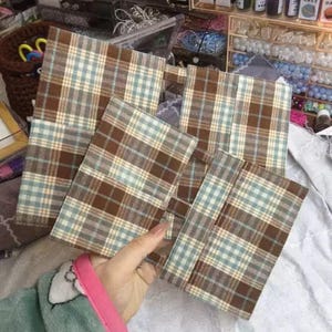 May include: A set of three ceramic mugs with a speckled, matte finish. The mugs are in shades of cream, light gray, and dark gray. Each mug has a simple, minimalist design and a rounded handle.