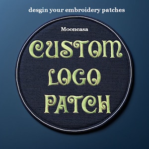 Puede incluir: Un parche redondo bordado de color negro con costuras blancas alrededor del borde. El parche dice "CUSTOM LOGO PATCH" en una fuente verde claro con remolinos decorativos.