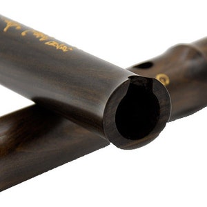 Puede incluir: Dos flautas chinas de madera marr&oacute;n oscuro, una parcialmente superpuesta a la otra. La flauta de arriba tiene letras doradas en la superficie. La flauta de abajo tiene un anillo dorado cerca de la boquilla.