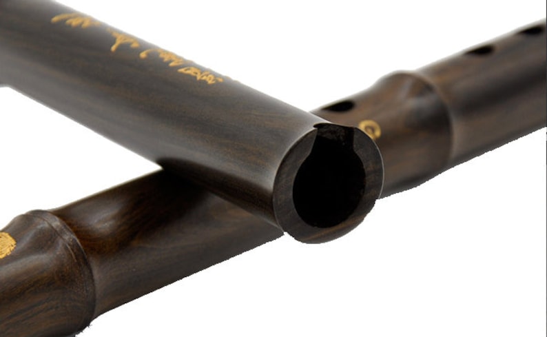 Puede incluir: Dos flautas chinas de madera marr&oacute;n oscuro, una parcialmente superpuesta a la otra. La flauta de arriba tiene letras doradas en la superficie. La flauta de abajo tiene un anillo dorado cerca de la boquilla.