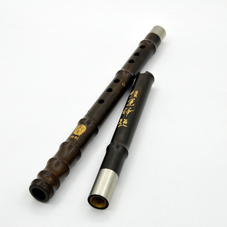 Puede incluir: Dos flautas chinas de madera marr&oacute;n oscuro con extremos de metal plateado. Las flautas tienen letras doradas y un dise&ntilde;o de le&oacute;n.