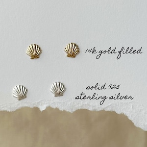 May include: A pair of gold-filled and a pair of sterling silver seashell stud earrings. The gold earrings are 14k gold filled. The silver earrings are solid 925 sterling silver. The text on the image reads "14k gold filled" and "solid 925 sterling silver".