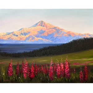 May include: An oil painting depicting a snow-capped mountain peak illuminated by golden light, situated behind a dark forest and a foreground meadow filled with vibrant pink fireweed flowers. The artist's signature is visible in the bottom left.