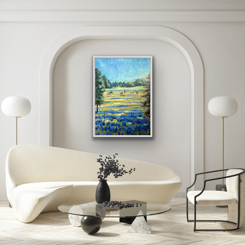 May include: A framed oil painting depicting a vibrant landscape with a field of bluebonnets in the foreground, a grassy meadow with grazing cattle in the mid-ground, and a bright blue sky above, all rendered with visible, textured brushstrokes.