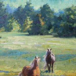 May include: An oil painting on canvas depicting two horses in a grassy field. One horse is light brown with a white mane, and the other is darker brown. The background features a dense line of green trees under a pale blue sky.