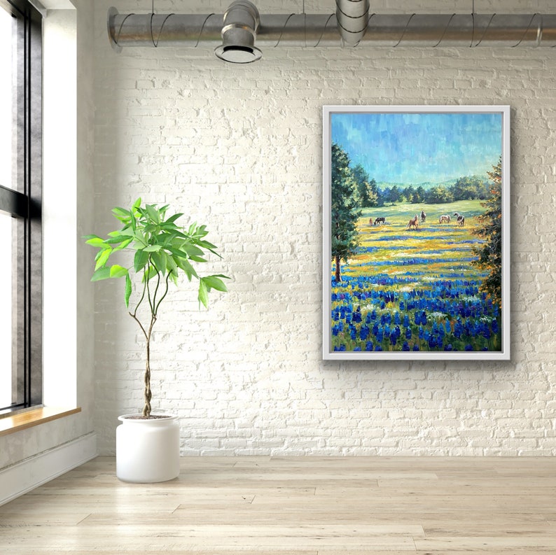 May include: A rectangular framed painting depicting a vibrant landscape with a field of blue and yellow wildflowers in the foreground, green trees on the sides, and several horses grazing in the distance under a bright blue sky.