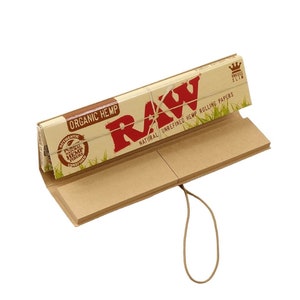 May include: A package of RAW Organic Hemp rolling papers, displayed open. The packaging is tan with red text that reads "RAW" and "Organic Hemp." The package is tied with a tan string. The words "Natural Unrefined Hemp Rolling Papers" are also visible.