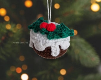 May include: A crocheted Christmas bauble shaped like a pudding with white icing and green holly leaves with red berries.