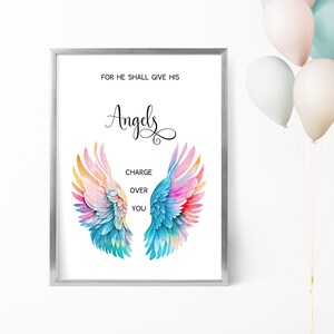 May include: A framed print with the words "FOR HE SHALL GIVE HIS Angels CHARGE OVER YOU." The artwork features watercolor angel wings in shades of blue, pink, orange, and yellow. The frame is silver. Pastel balloons are in the background.
