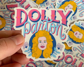 May include: A sticker featuring a cartoon illustration of Dolly Parton with the text "DOLLY PARTON" in pink and blue lettering. The sticker has a white background with blue and pink floral accents.