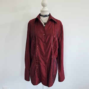 May include: A long-sleeved button-down shirt in a deep burgundy red colour. The shirt features a pointed collar and two vertical panels of dark, shimmering sequin embellishments running down the front. It is displayed on a white mannequin.