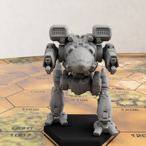 Puede incluir: Un modelo gris impreso en 3D de un robot mech, de pie sobre una base negra. El robot tiene un diseño detallado con lanzadores de misiles en los hombros. Está posicionado sobre un tablero de juego hexagonal con elementos de terreno y marcas numéricas.