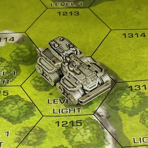 May include: A silver miniature tank with a detailed design, sitting on a green game board with the text "LEVEL 1" and "LIGHT" printed on it.