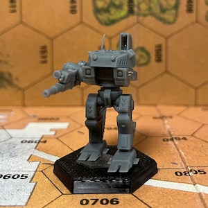 May include: A grey plastic miniature of a robot with a large gun, standing on a black hexagonal base. The robot has a detailed design with a large head and a long gun arm.