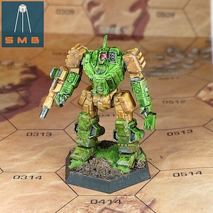 May include: A green and gold painted miniature robot figure standing on a black hexagonal base with green grass and brown dirt. The robot is holding a gun in its right hand.