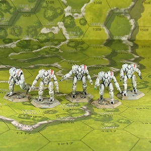 Puede incluir: Cinco robots en miniatura pintados de blanco y gris con detalles rojos se encuentran sobre bases hexagonales. Los robots están en posición de batalla. Las bases están sobre un tablero de juego hexagonal verde y marrón con números y texto.