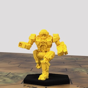 May include: A yellow plastic miniature robot figure standing on a black base. The robot has a humanoid shape with a large head and two arms with weapons.