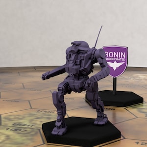 Op de afbeelding: Een paars plastic miniatuur robotmodel met een zwarte basis en een wit logo met de tekst "RONIN INCORPORATED" op een schild. De robot staat op een zeshoekige tegel met het nummer "1008" erop.