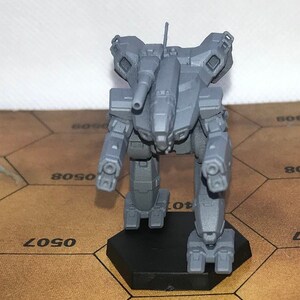 Könnte beinhalten: Ein graues Plastikmodell eines Mech-Roboters mit einer großen Kanone auf dem Rücken. Der Roboter steht auf einem schwarzen sechseckigen Sockel.