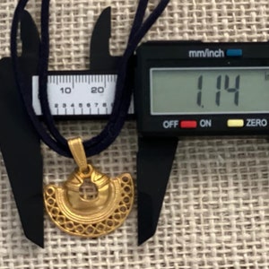 May include: A gold pendant necklace with a decorative design. The pendant is 1.14 inches in diameter.