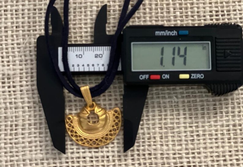 May include: A gold pendant necklace with a decorative design. The pendant is 1.14 inches in diameter.