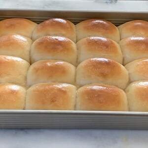 May include: A baking dish filled with 12 golden brown dinner rolls.