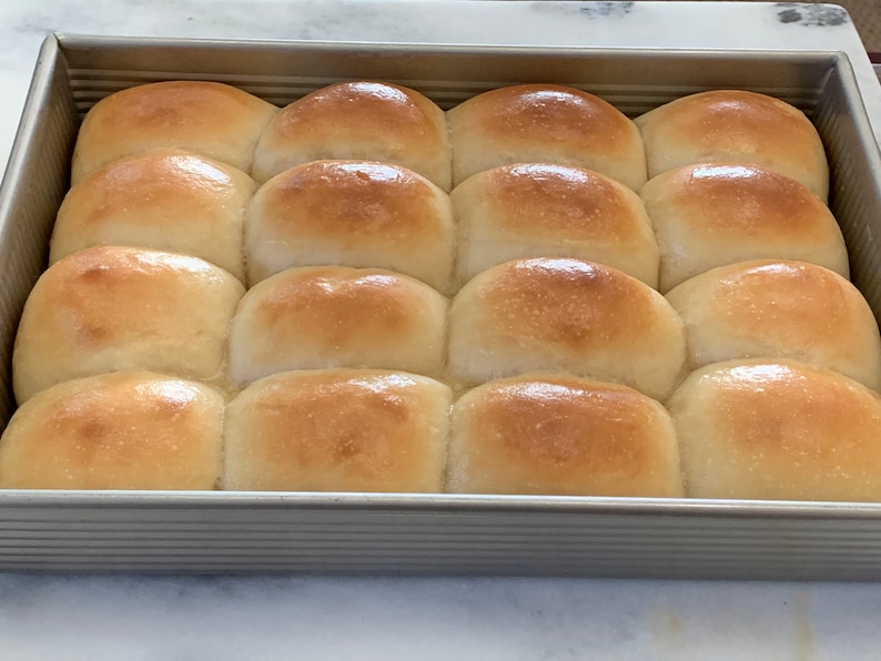 May include: A baking dish filled with 12 golden brown dinner rolls.