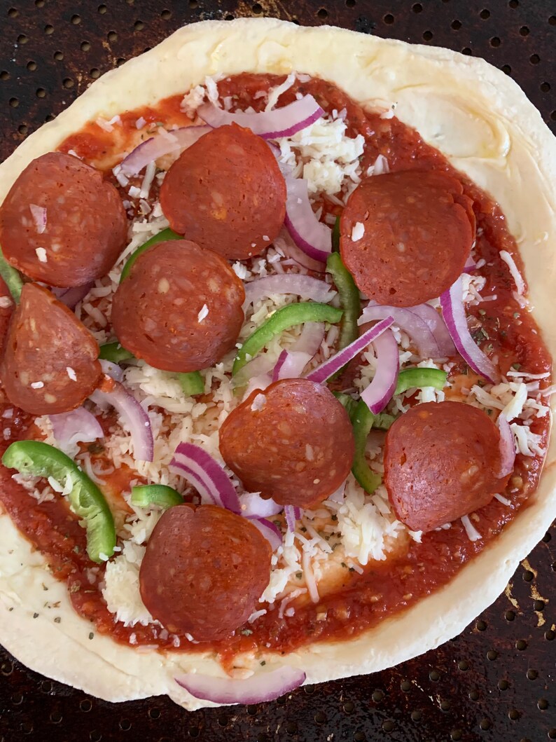 May include: A pizza crust topped with tomato sauce, mozzarella cheese, pepperoni slices, red onion, and green bell pepper.