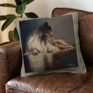 Puede incluir: Una almohada con una pintura de un perro Collie durmiendo sobre un fondo marrón claro. La almohada tiene una tela beige con un patrón sutil y el texto "Parnell Studios" en la esquina inferior derecha.