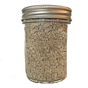 May include: A glass jar with a silver lid filled with a light brown powder.