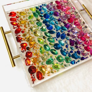 May include: A clear acrylic tray with gold handles filled with colorful rhinestones arranged in a rainbow pattern.