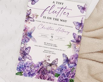 May include: A white baby onesie with a baby shower invitation. The invitation features purple butterflies and flowers with the text "A Tiny Flutter Is On The Way". The invitation also includes the date and time of the baby shower.