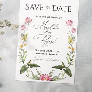 Op de afbeelding: Een trouwkaart met bloemenillustraties en de tekst "SAVE the DATE". De namen "Mugdha" en "Rajesh" zijn in cursief geschreven. De datum en locatie zijn inbegrepen, samen met de zin "Formal invite to follow."
