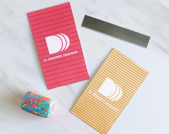 May include: Two business cards with a white logo of a stylized letter D on a red and a yellow background. The logo text reads "D. DESIREE DESIGNS".