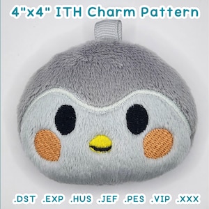 May include: A soft, grey penguin charm with black eyes, orange cheeks, and a yellow beak. The charm measures approximately 10 cm by 10 cm and has a small loop at the top. Text on the image reads "4"x4" ITH Charm Pattern" and lists embroidery file formats.