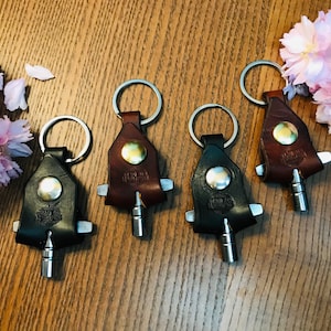 May include: Five leather keychains with metal key rings and a small metal tool attached. The keychains are brown and black and have a metal button with the text "Harley Davidson" on them.