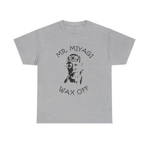 May include: A gray t-shirt with a black and white illustration of Mr. Miyagi from the Karate Kid movie. The text "MR. MIYAGI" is above the illustration and "WAX OFF" is below.