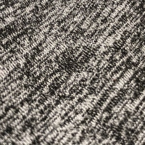 May include: Close-up of a gray and black knitted fabric with a textured pattern.