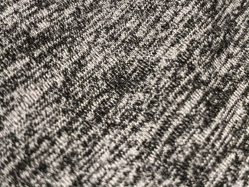 May include: Close-up of a gray and black knitted fabric with a textured pattern.