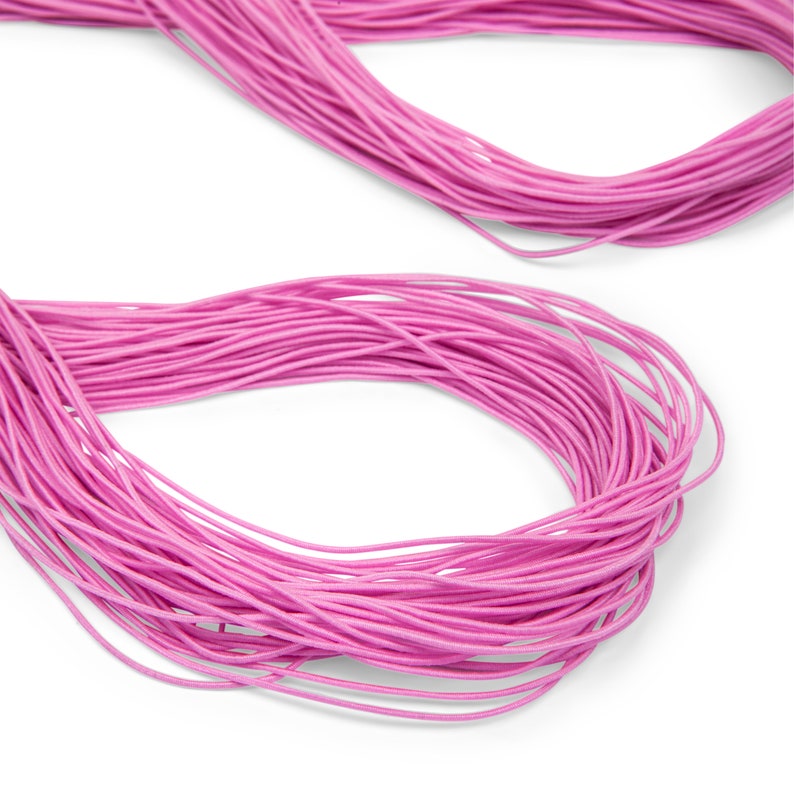 May include: A close-up of a spool of pink elastic cord. The cord is wound tightly and is ready to be used for crafting projects.