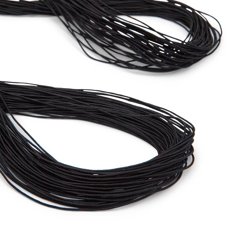 May include: Two bundles of black elastic cord against a white background. The cords are tightly wound, with a slightly glossy appearance. The image is a close-up, highlighting the texture and color of the material, suitable for crafting or sewing projects.