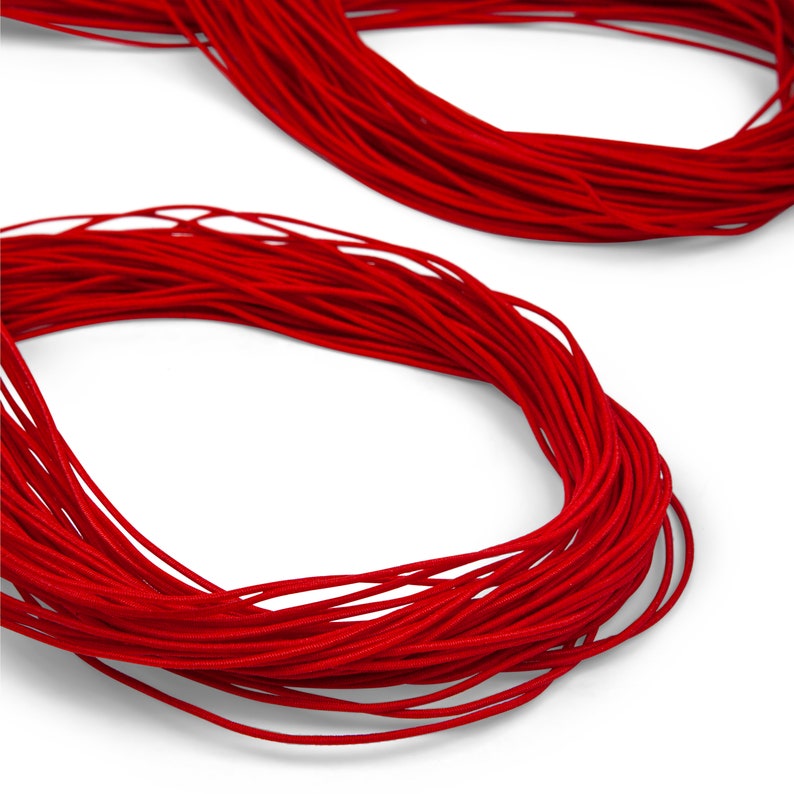 Puede incluir: Un carrete de cord&oacute;n el&aacute;stico rojo brillante, perfecto para proyectos de manualidades.