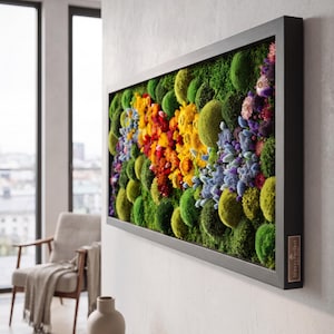 May include: A rectangular wall art piece featuring a black frame filled with preserved green moss mounds and clusters of colorful dried flowers in shades of yellow, orange, red, blue, and purple. A small label on the frame reads MossyPerfect.