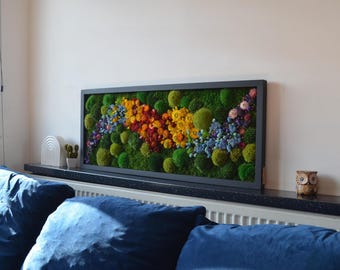 May include: A rectangular framed wall art piece featuring a vibrant arrangement of preserved moss and flowers. The artwork showcases a colorful display of green, yellow, red, and blue hues, creating a natural and decorative element.