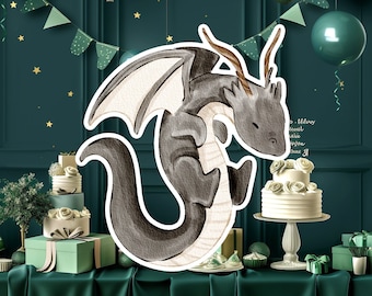 Puede incluir: Un dragón negro y gris con alas blancas está volando frente a un fondo verde y blanco con globos y pasteles. El dragón está mirando hacia abajo a un pastel blanco con flores blancas en la parte superior.