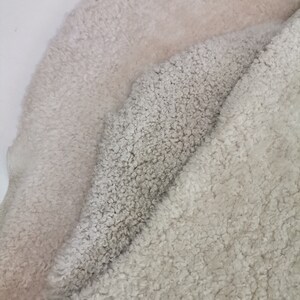 May include: Two pieces of soft, fluffy, white faux fur fabric. The fabric is folded in half, with the lighter side of the fabric on top.