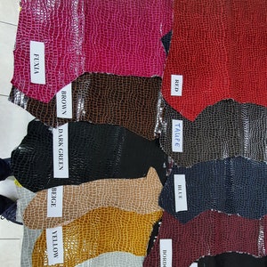 May include: A variety of leather samples in different colors, including fuchsia, brown, dark green, beige, yellow, light grey, red, taupe, blue, bordo, and black. Each sample has a crocodile-embossed texture.