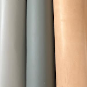 Puede incluir: Tres rollos de cuero en diferentes colores: gris claro, gris y natural. El cuero est&aacute; enrollado y los extremos son visibles.