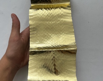 Peut inclure: Une longue bande de cuir de serpent de couleur dorée. Le cuir a une surface texturée et est plié en deux.