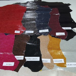 May include: A variety of leather samples in different colors, including red, taupe, blue, bordo, brown, dark green, beige, yellow, and light gray. Each sample has a crocodile-embossed pattern.